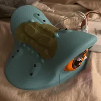 Imagem enviada pelo cliente. Clique para ver mais detalhes. A imagem representa: Sapato Blue Crocs em uma cama com o que parece ser um picles ou objeto verde colocado em cima